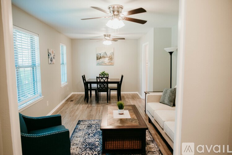 A living room with a sofa, a chair, a coffee table, and a ceiling fan.