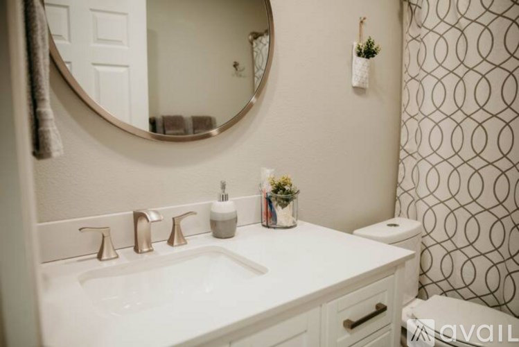 A bathroom with a white sink and a round mirror above it.
