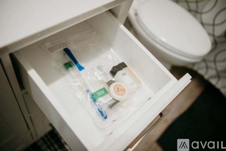 A drawer in a bathroom cabinet is open, revealing a toothbrush, a bottle of mouthwash, and a tube of toothpaste.