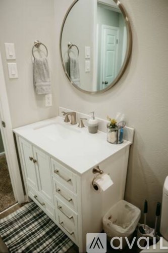 A bathroom with a white sink and a round mirror.