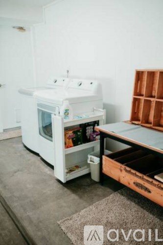 A white microwave oven with its door open and a wooden table with drawers in front of it.