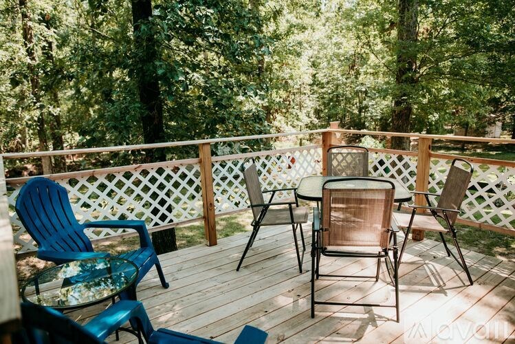 A wooden deck with a table and chairs is surrounded by trees.