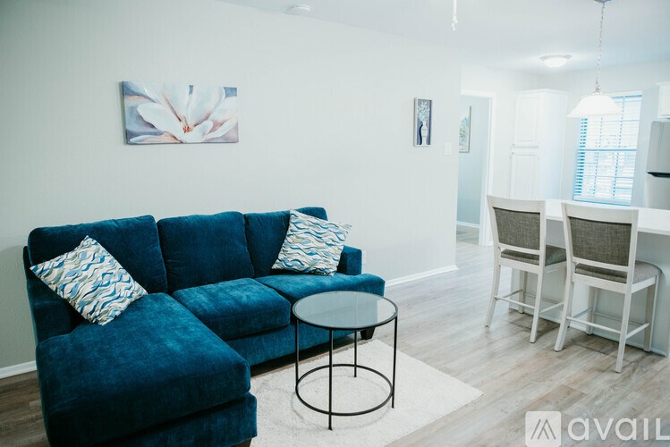 A blue velvet couch with a small table in front of it.