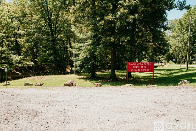 A sign in front of trees that says "Bayou Meto Creek Canoe Trail".