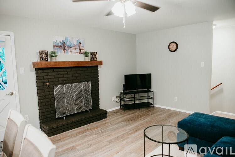 A living room with a fireplace, a television, and a ceiling fan.
