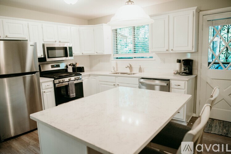A kitchen with white cabinets and a marble countertop.