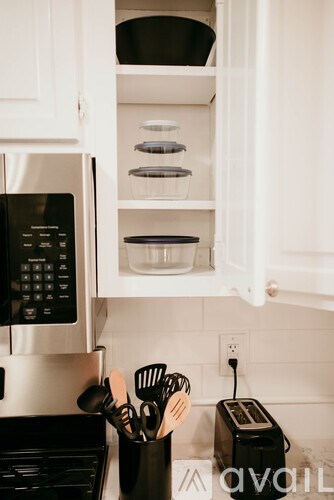 A kitchen with a microwave, toaster, and utensils.