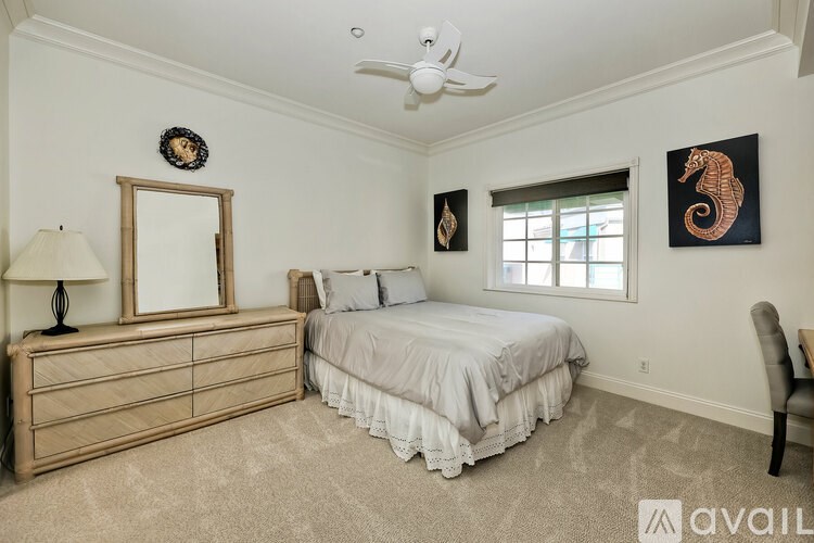 A bedroom with a bed, dresser, and ceiling fan.