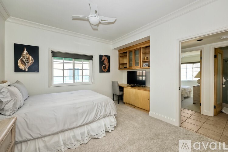 A bedroom with a bed, a ceiling fan, and a television.
