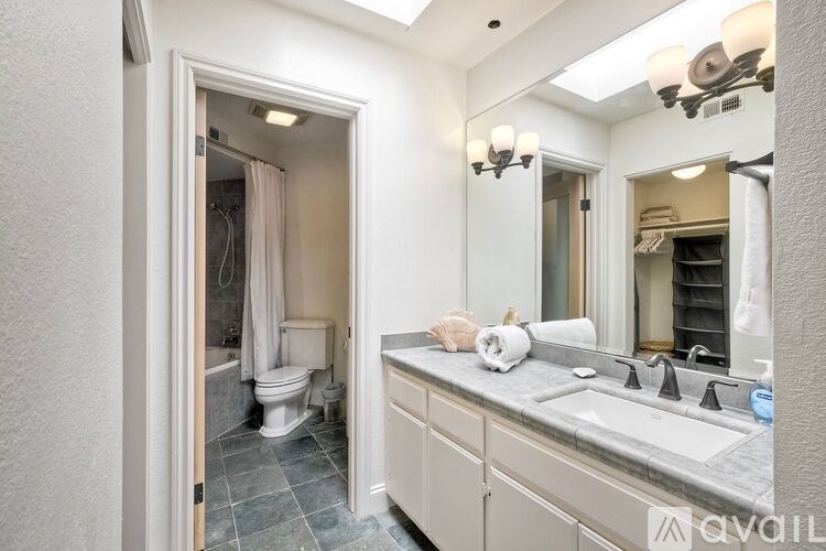 A bathroom with a toilet, sink, and mirror.