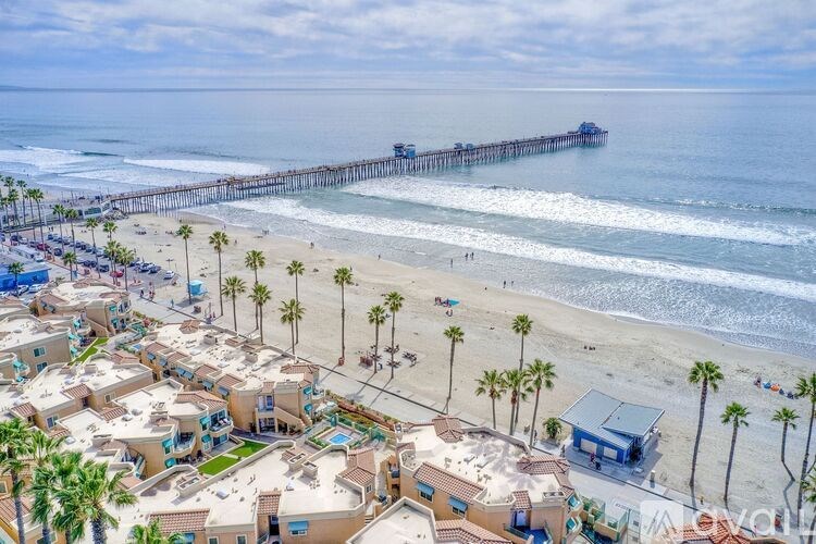 A beachfront community with a pier in the distance.