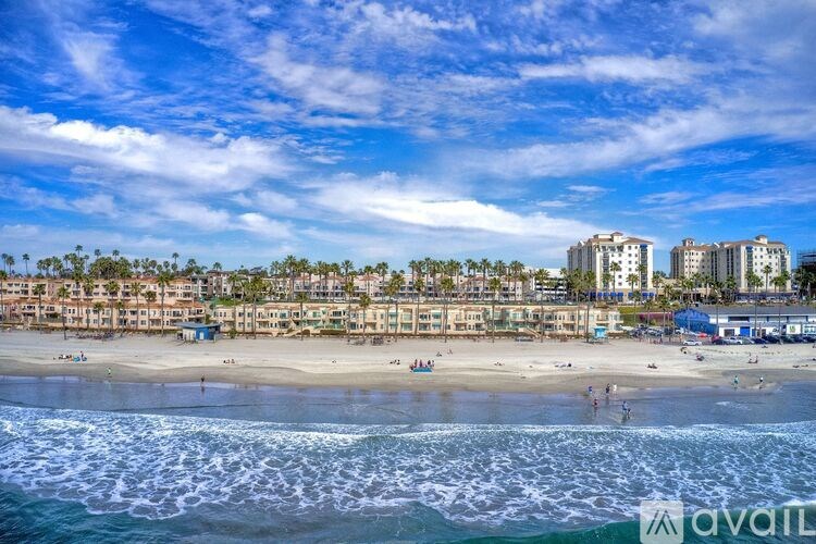 A beach scene with buildings in the background and people on the sand.