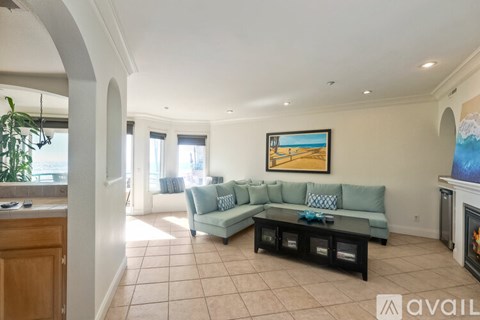 A living room with a grey couch and a painting on the wall.