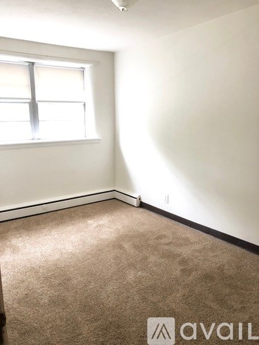 A carpeted room with a window and Avail logo.