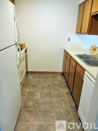 A kitchen with a white fridge and brown cabinets.