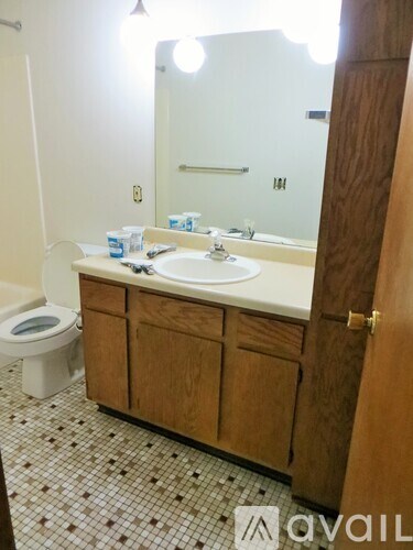 A bathroom with a toilet, sink, and mirror.