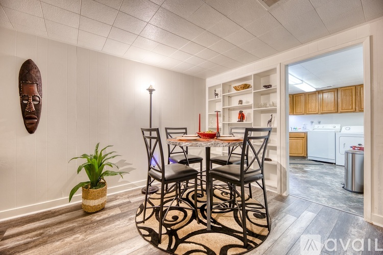 A dining room with a table set for four and a plant on the floor.