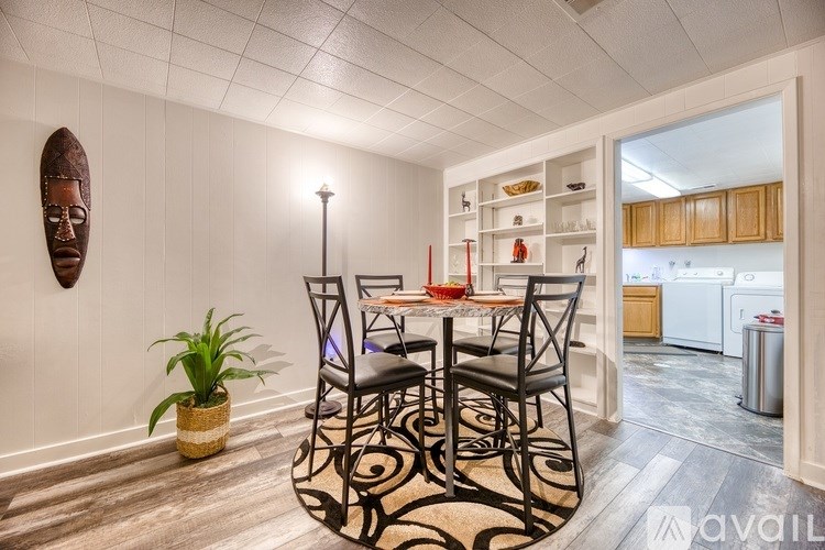 A dining room with a table set for four and a plant on the floor.