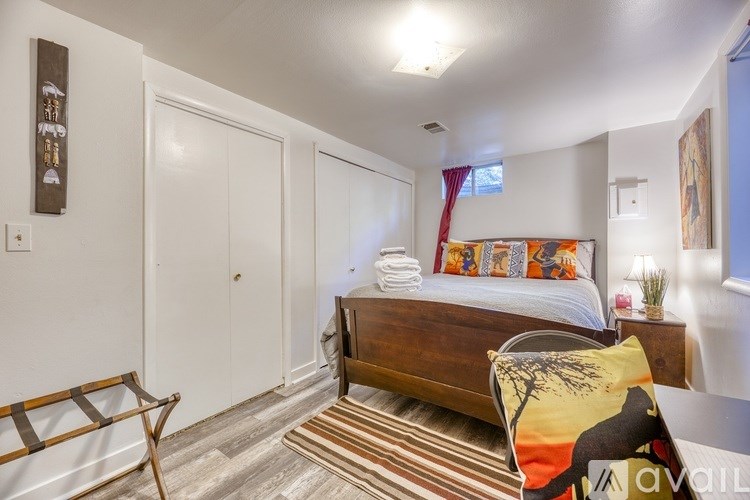 A bedroom with a bed, a chair, and a rug.