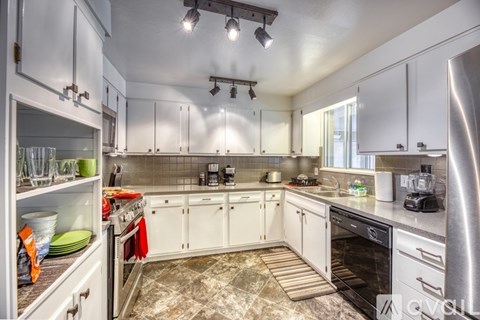 A modern kitchen with white cabinets and stainless steel appliances.
