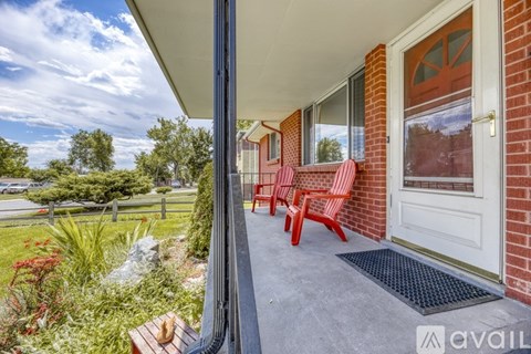 A red chair is on the porch of a house.