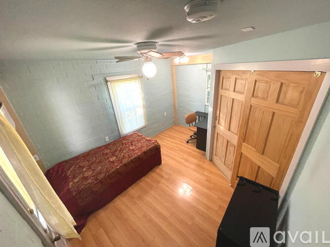 A room with a bed, desk, and a ceiling fan.
