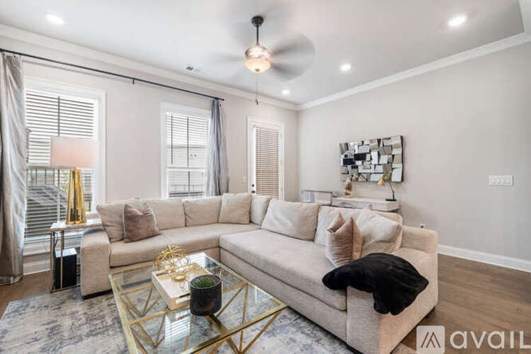 A living room with a beige sofa, a glass coffee table, and a ceiling fan.