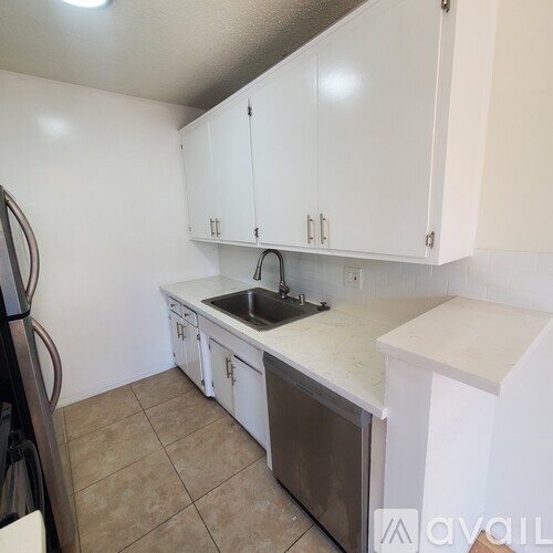 A kitchen with white cabinets and a tiled floor.
