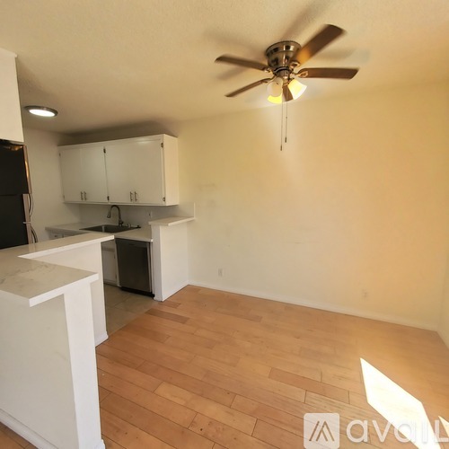 A room with a ceiling fan and wooden flooring.