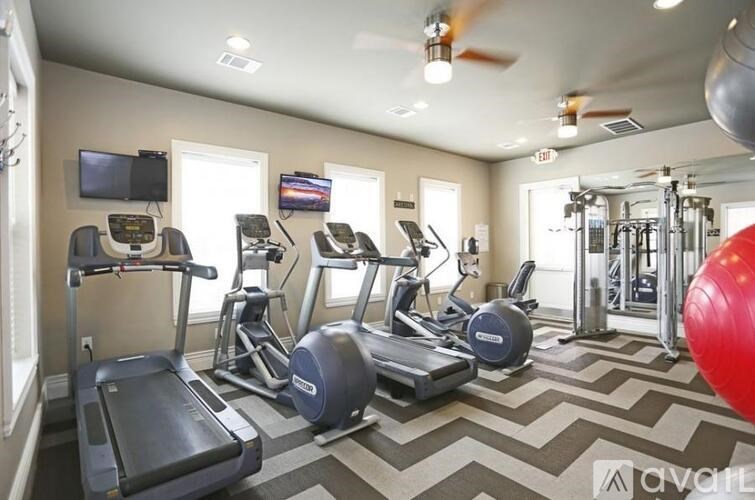 A gym with treadmills, elliptical machines, and a red exercise ball.