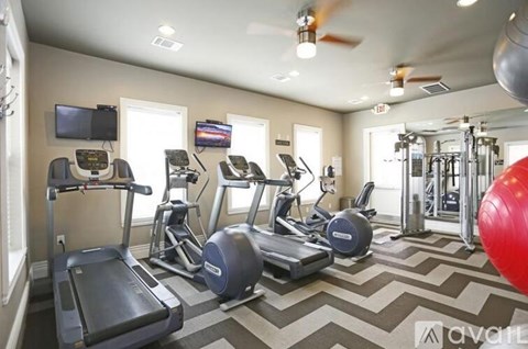 A gym with treadmills, elliptical machines, and a red exercise ball.