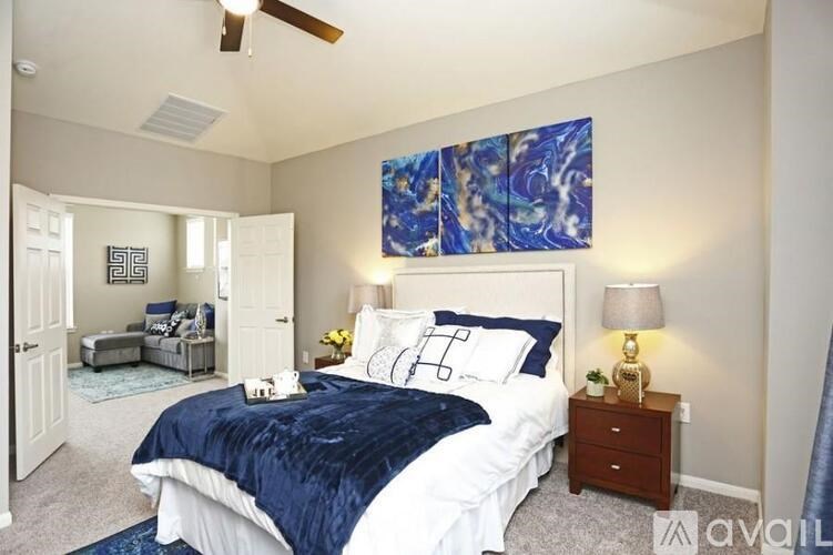 A bedroom with a large bed and a blue and white painting on the wall.