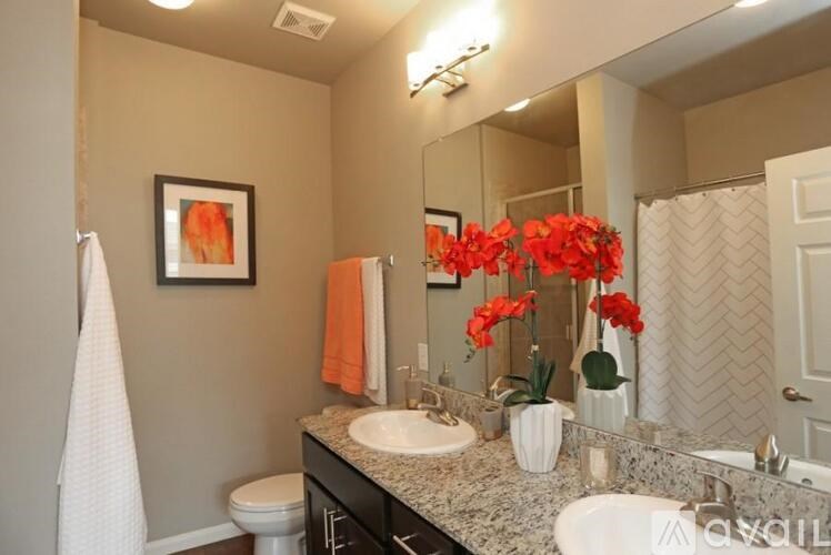 A bathroom with a toilet, sink, mirror, and a vase of flowers.