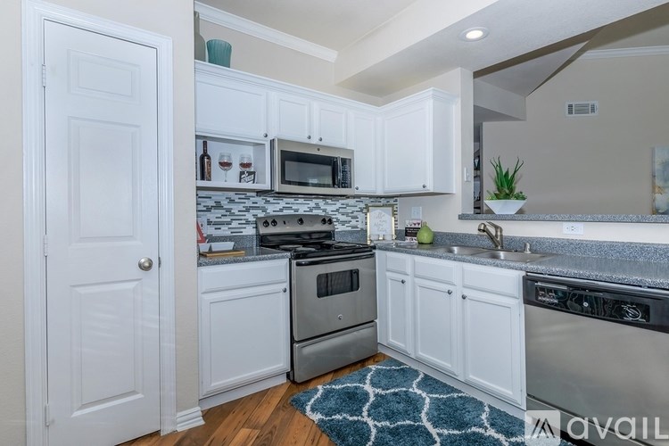 A kitchen with white cabinets and a patterned rug on the floor.