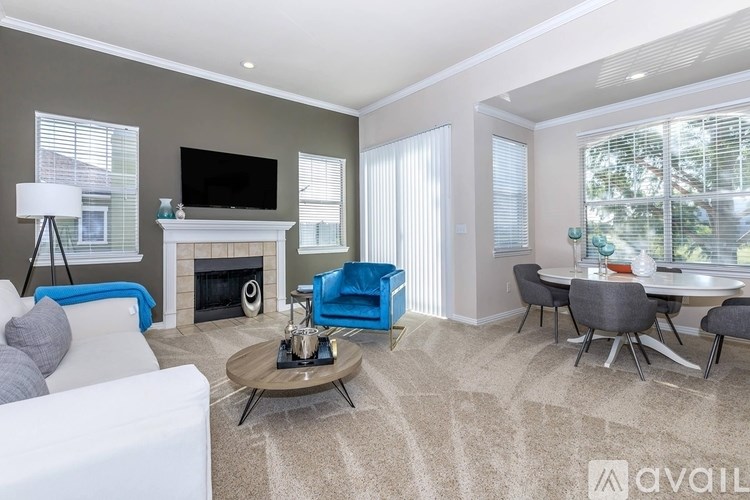 A living room with a fireplace, a white couch, a blue chair, a coffee table, and a television.