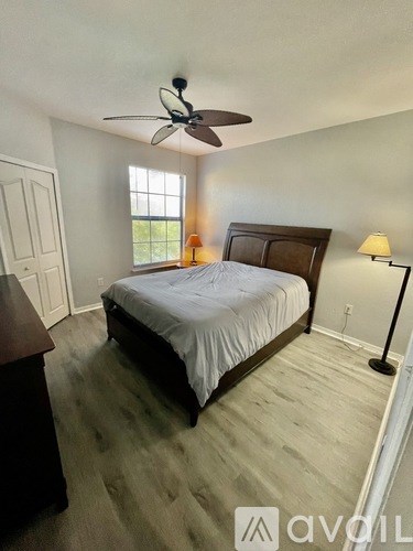 A bedroom with a bed, nightstand, and window.