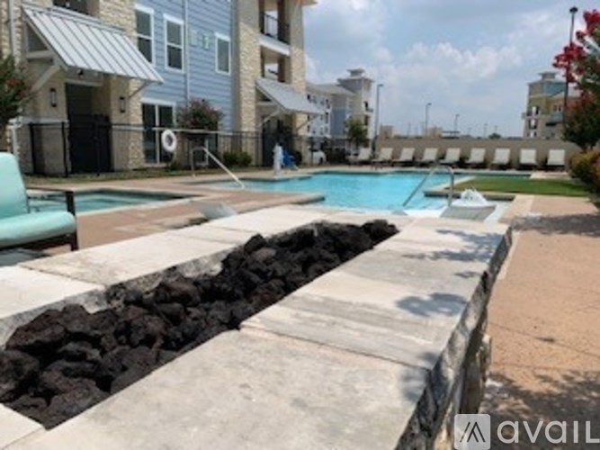 A swimming pool surrounded by a stone wall and a concrete walkway.