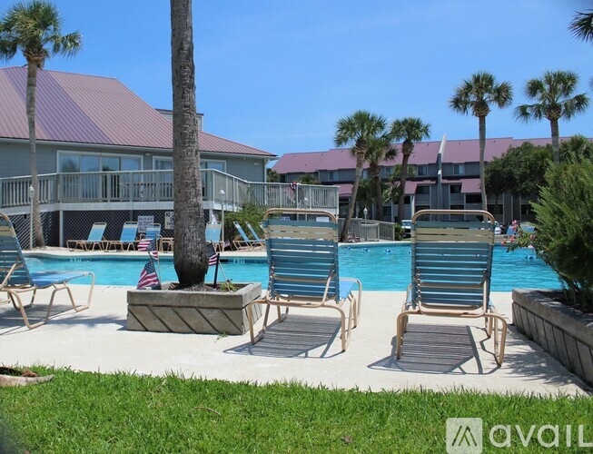 A pool area with lounge chairs and a palm tree.