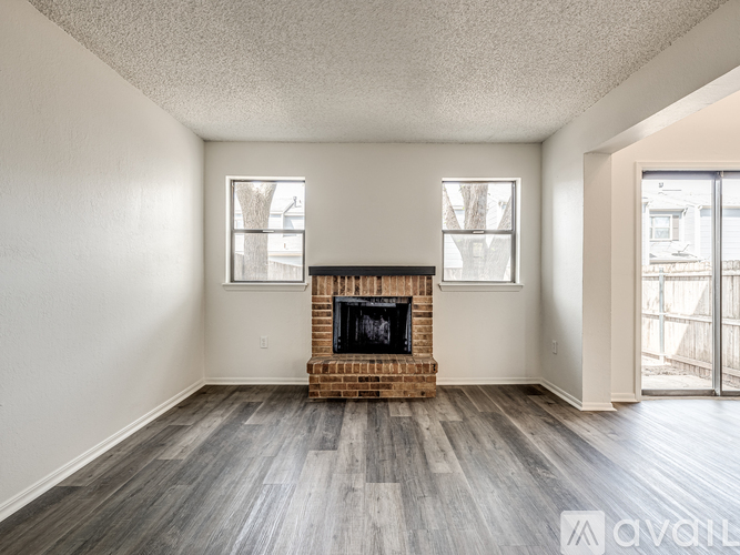 A living room with a fireplace and two windows.