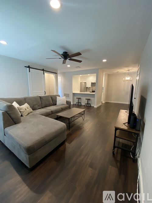 A living room with a grey couch and a ceiling fan.