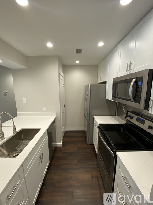 A kitchen with white cabinets and black appliances.