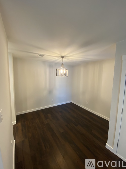 A long hallway with a light on the ceiling and a wooden floor.