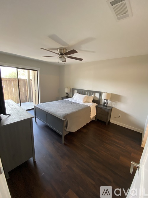 A bedroom with a bed, nightstand, and a ceiling fan.