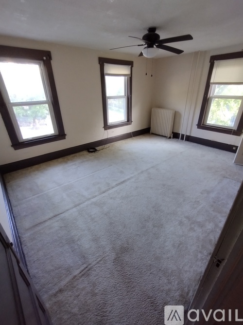 A room with a ceiling fan and three windows.