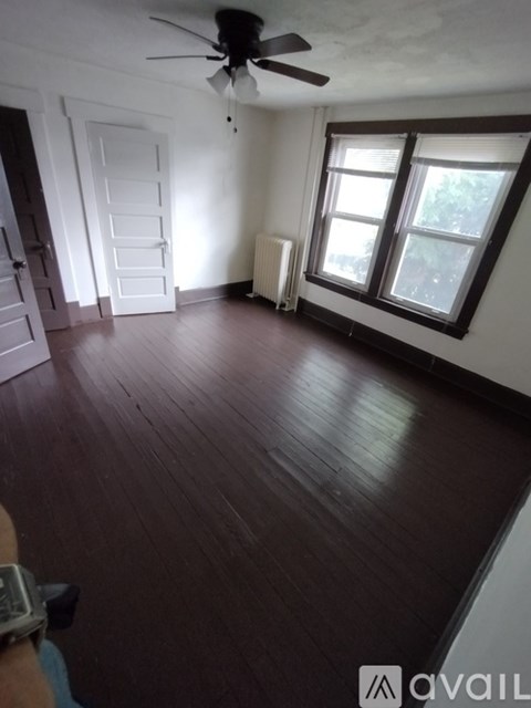 A room with a ceiling fan and wooden flooring.