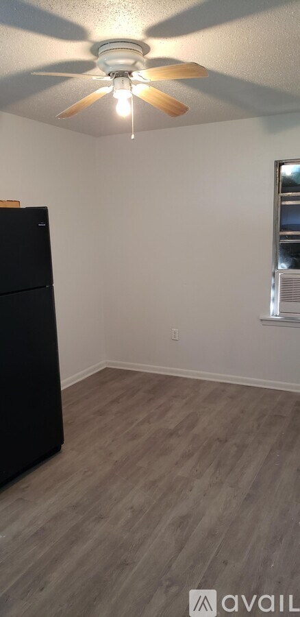 A room with a ceiling fan and a black refrigerator.