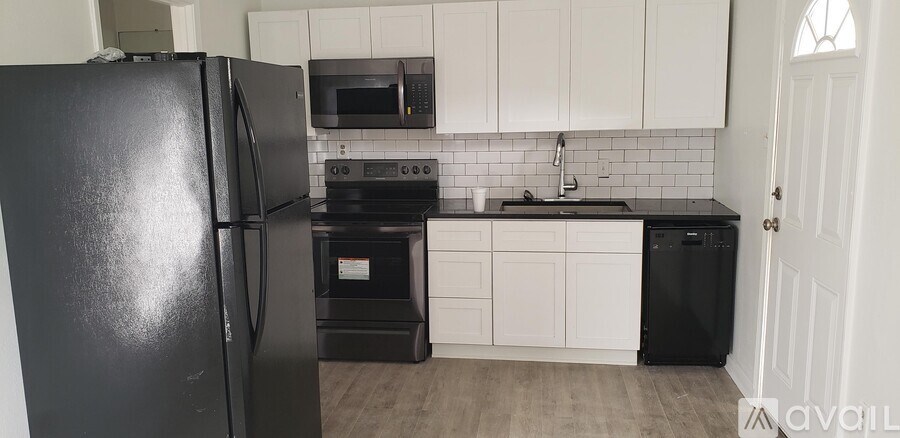 A black refrigerator in a kitchen with white cabinets.