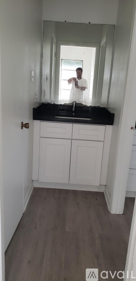 A person is taking a selfie in a bathroom with a black countertop.
