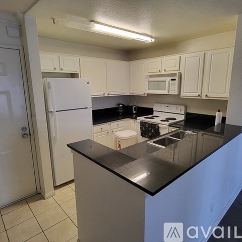 A kitchen with white cabinets and black countertops.