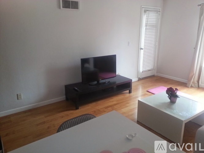 A room with wooden flooring and a window with curtains.